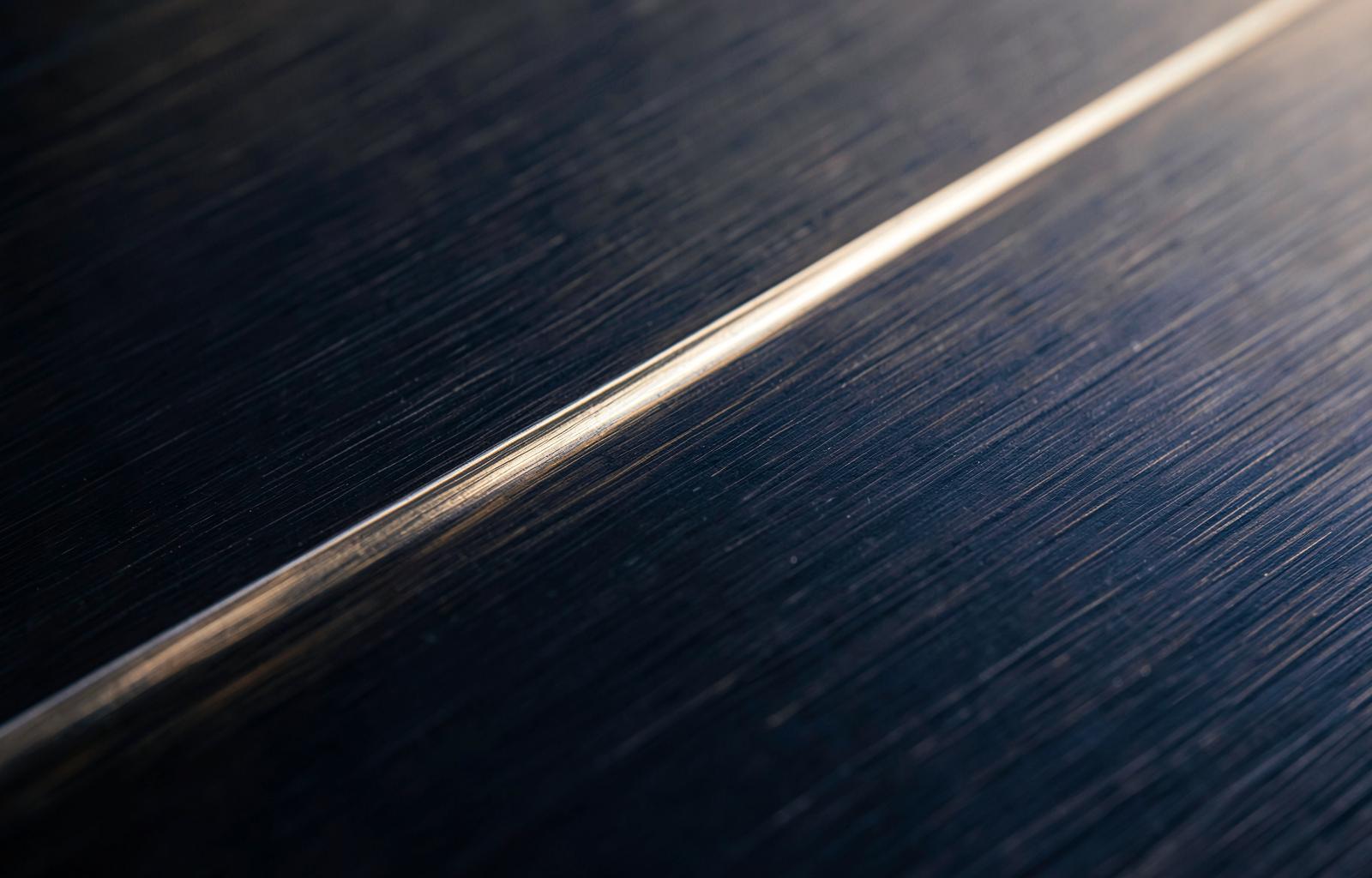 Macro detail of brushed dark metal catching warm light